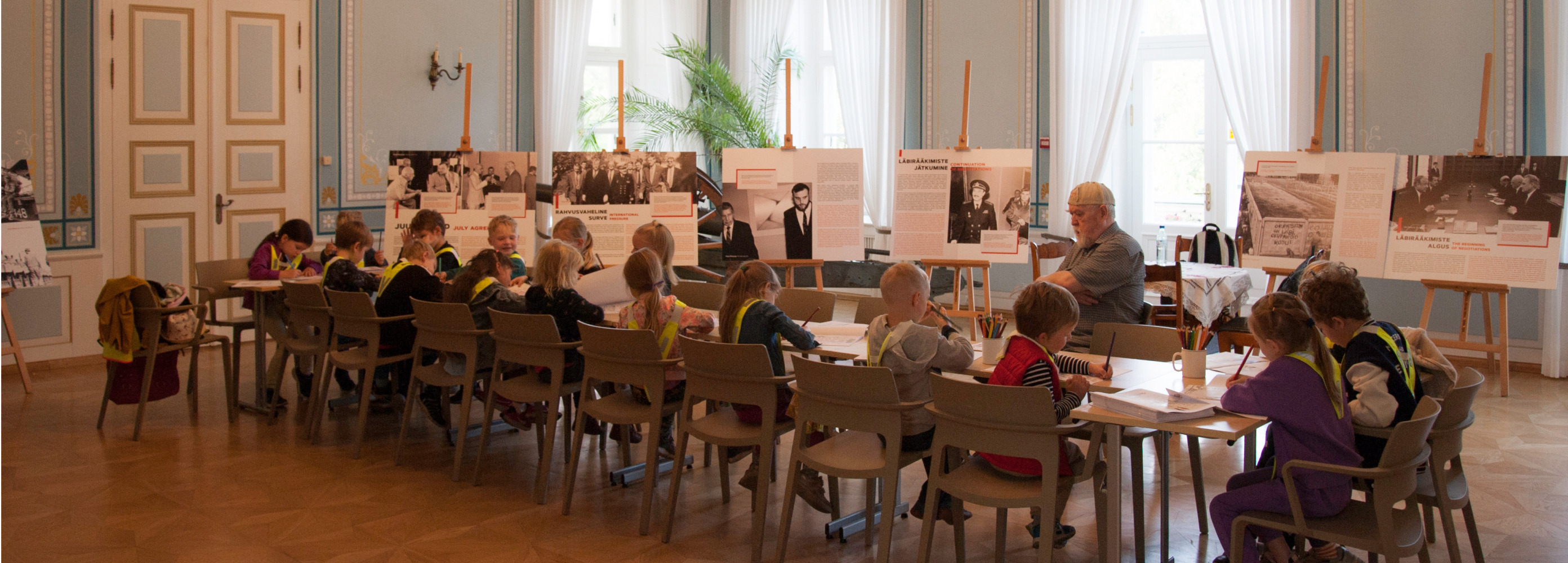 Lapsed Eesti sõjamuuseumi saalis laua taga joonistamas.